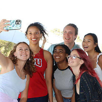 Six students looking at a cell phone for selfie